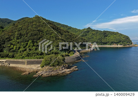 大分県臼杵市の海岸沿い道路と緑の山を俯瞰した空撮写真 140009429