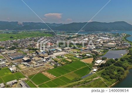 宮崎県延岡市の市街地・水田・太陽光パネルと湾岸を俯瞰した空撮写真 140009654
