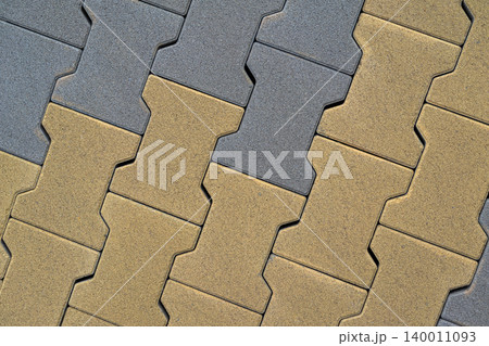 Gray and yellow pavement blocks create geometric pattern with concrete joints, rough surface. Natural background with pavement texture for construction, architecture, landscaping, mockup use 140011093