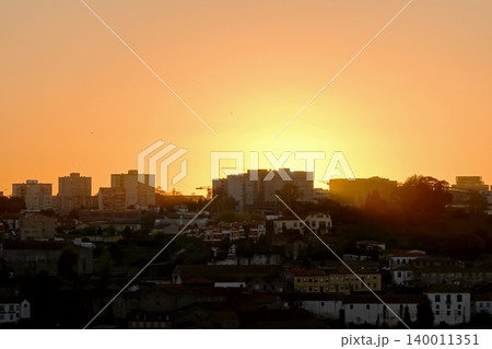 Golden sunset over the city silhouette and residential buildings in Porto, Portugal Golden sunset over the city silhouette and residential buildings in Porto, Portugal 140011351