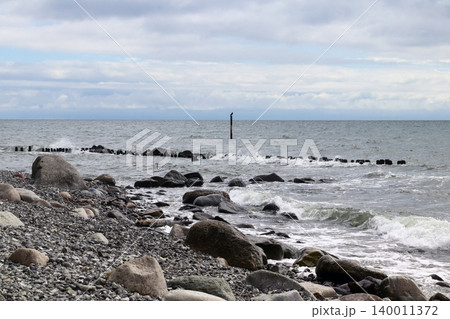 Rocky Shoreline With Waves Crashing Under Overcast Sky and Solitary Marker Post Rocky Shoreline With Waves Crashing Under Overcast Sky and Solitary Marker Post 140011372