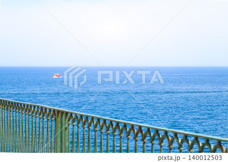Small boat sails across the vast blue ocean under a bright clear sky Small boat sails across the vast blue ocean under a bright clear sky 140012503