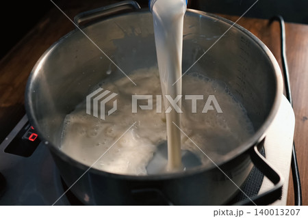 Pouring milk into the pan on scales. Pouring milk into the pan on scales. 140013207