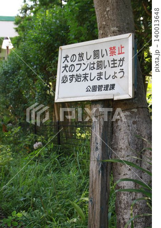 公園の木に取り付けられた「犬の放し飼い禁止・フンの始末」を促す注意看板 140013648