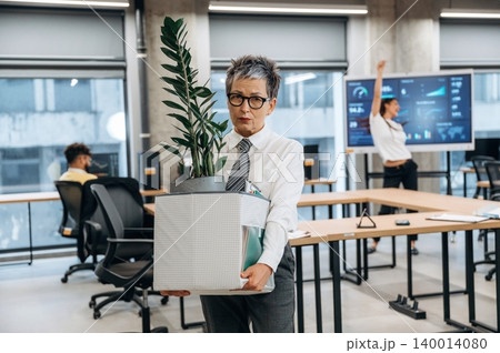 Businesswoman carrying potted plant and office supplies in modern workspace, showcasing a dynamic work environment and team collaboration concept Businesswoman carrying potted plant and office supplies in modern workspace, showcasing a dynamic work environment and team collaboration concept 140014080