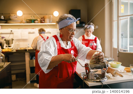 Senior African American woman making pasta dough in a commercial kitchen 140014196