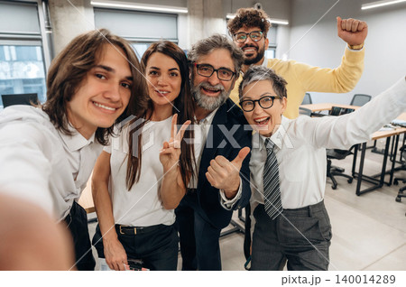 Group of diverse professionals smiling and posing for a selfie in a modern business office, showcasing teamwork and positive workplace atmosphere Group of diverse professionals smiling and posing for a selfie in a modern business office, showcasing teamwork and positive workplace atmosphere 140014289