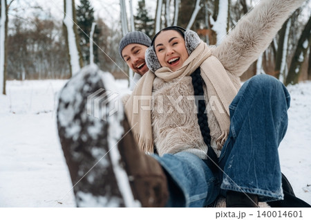 Joyful couple enjoying winter fun in snowy landscape, laughing and playing together, showcasing happiness and connection in a beautiful outdoor setting 140014601