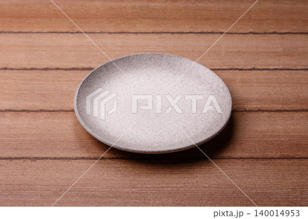 An empty ceramic round plate, kitchen utensils for a dinner table. An empty plate An empty ceramic round plate, kitchen utensils for a dinner table. An empty plate 140014953