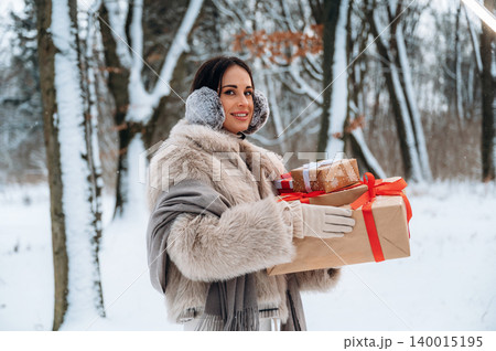 Woman with dark hair wearing winter attire holds beautifully wrapped gifts in snowy forest, showcasing festive spirit and holiday joy in a serene winter landscape Woman with dark hair wearing winter attire holds beautifully wrapped gifts in snowy forest, showcasing festive spirit and holiday joy in a serene winter landscape 140015195