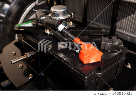 Close up of electric vehicle battery system with orange high voltage cables and metal components Close up of electric vehicle battery system with orange high voltage cables and metal components 140016423