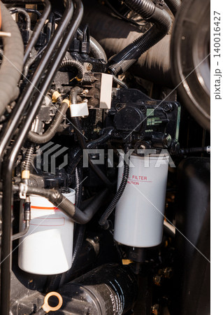 Close Up of Industrial Diesel Engine with White Oil Filters and Black Wires and Hoses Close Up of Industrial Diesel Engine with White Oil Filters and Black Wires and Hoses 140016427