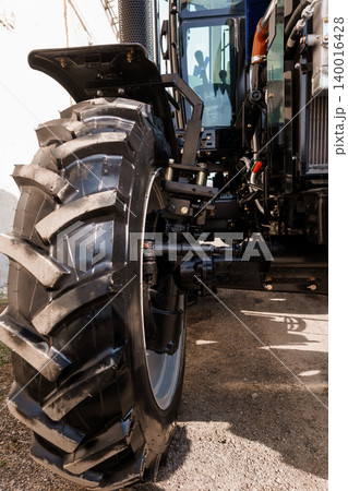 Close Up of Heavy Duty Black Tractor Tire and Mudguard on Sunny Farm Field Close Up of Heavy Duty Black Tractor Tire and Mudguard on Sunny Farm Field 140016428