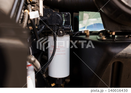 Close Up of White Fuel Filter and Black Engine Components in Industrial Machine Setting Close Up of White Fuel Filter and Black Engine Components in Industrial Machine Setting 140016430