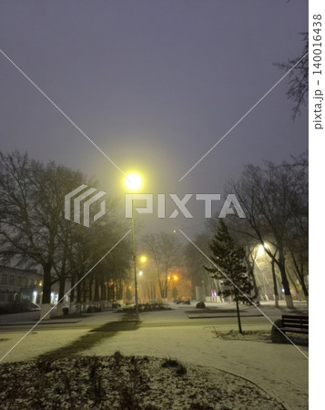 A peaceful winter night in a park, with snow covering the ground and warm street lamps casting soft shadows. The serene atmosphere invites quiet contemplation and leisurely strolls. A peaceful winter night in a park, with snow covering the ground and warm street lamps casting soft shadows. The serene atmosphere invites quiet contemplation and leisurely strolls. 140016438