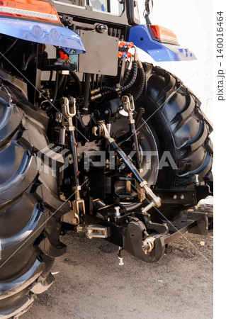 Rear View of Blue Agricultural Tractor with Heavy Duty Hitch and Large Treaded Tires in Daylight Rear View of Blue Agricultural Tractor with Heavy Duty Hitch and Large Treaded Tires in Daylight 140016464