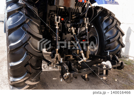 Rear View of Black Tractor Tires and Hydraulic Hitch System on Farm Equipment in Daylight Rear View of Black Tractor Tires and Hydraulic Hitch System on Farm Equipment in Daylight 140016466