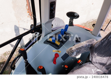 Interior View of Modern Tractor Cabin with Control Levers and Grey Dashboard in Bright Sunlight Interior View of Modern Tractor Cabin with Control Levers and Grey Dashboard in Bright Sunlight 140016478