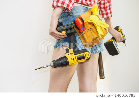 Woman with toolbelt and drill Woman with toolbelt and drill 140016793