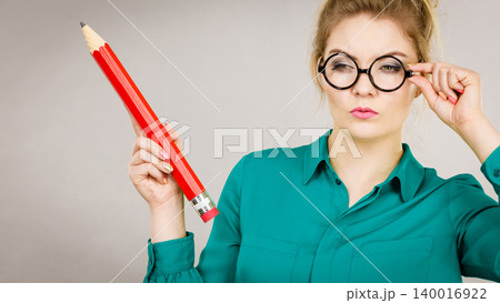 Woman confused thinking, big pencil in hand Woman confused thinking, big pencil in hand 140016922
