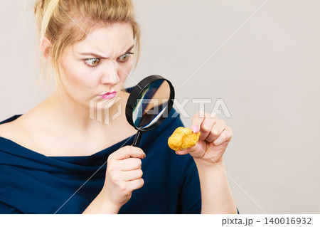 Woman holding magnifying glass investigating bread Woman holding magnifying glass investigating bread 140016932
