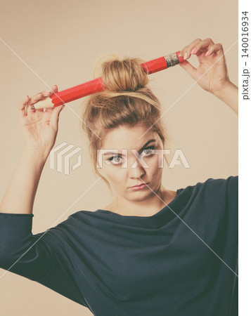 Confused blonde woman having big pencil in hair Confused blonde woman having big pencil in hair 140016934