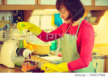Woman make vegetables juice in juicer machine Woman make vegetables juice in juicer machine 140017066