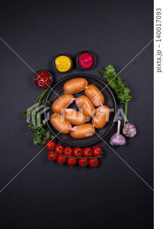 Mini sausages with sauces, tomatoes, garlic, and parsley on dark background Mini sausages with sauces, tomatoes, garlic, and parsley on dark background 140017093