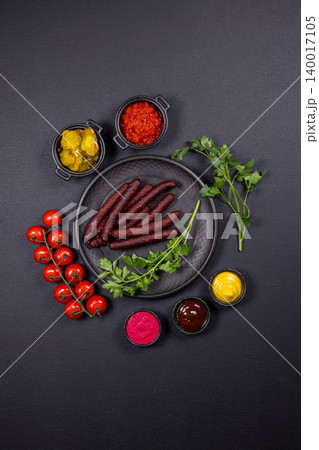 Cooked sausage platter with fresh cherry tomatoes and sauces 140017105