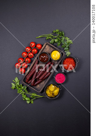 Smoked sausages with various condiments and fresh vegetables Smoked sausages with various condiments and fresh vegetables 140017108