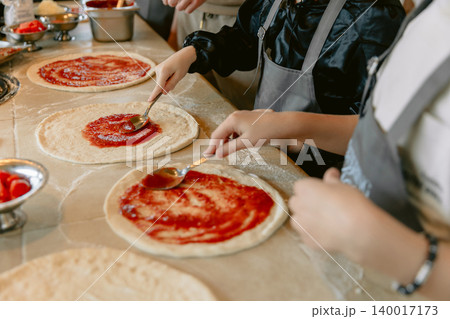 Chef preparing fresh pizza in restaurant kitchen with tomato sauce Chef preparing fresh pizza in restaurant kitchen with tomato sauce 140017173