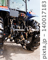Rear View of Modern Blue Farm Tractor with Hydraulic Hitch and Large Treaded Tires on Sand 140017183