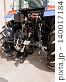 Rear View of Blue Agricultural Tractor Showing Hydraulic Hitch and Large Rubber Tires on Concrete 140017184