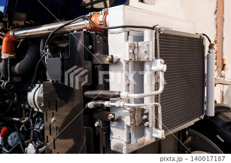 Close up of industrial radiator and engine components with metal pipes and silver cooling fins Close up of industrial radiator and engine components with metal pipes and silver cooling fins 140017187