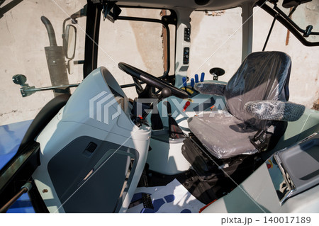 Interior view of modern heavy machinery cabin with driver seat and steering wheel in blue and gray tones Interior view of modern heavy machinery cabin with driver seat and steering wheel in blue and gray tones 140017189