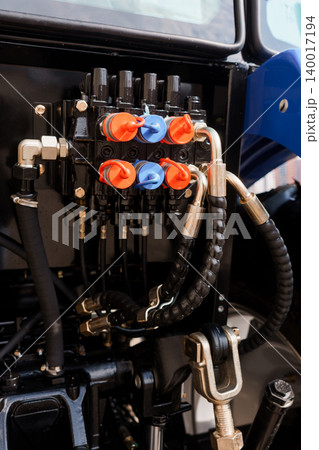 Close Up of Hydraulic Control Valves and Black Rubber Hoses on Blue Agricultural Tractor Machine Close Up of Hydraulic Control Valves and Black Rubber Hoses on Blue Agricultural Tractor Machine 140017194