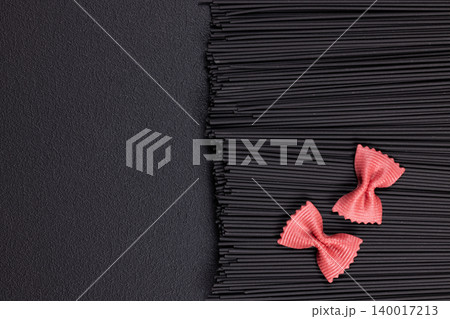 Black squid ink spaghetti contrasting with pink farfalle Black squid ink spaghetti contrasting with pink farfalle 140017213
