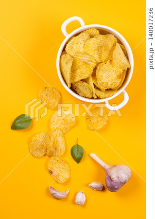 Wavy potato chips with garlic and fresh basil 140017236
