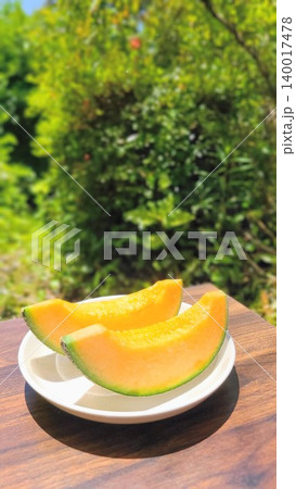 新緑が美しい屋外で撮影された白いお皿に並ぶ瑞々しい赤肉カットメロン 新緑が美しい屋外で撮影された白いお皿に並ぶ瑞々しい赤肉カットメロン 140017478