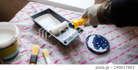 Hand dipping roller into paint tray. Self made home improvement on budget. Cosmetic renovation Hand dipping roller into paint tray. Self made home improvement on budget. Cosmetic renovation 140017863