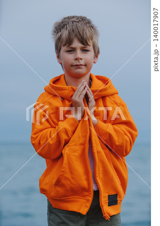 Portrait of boy standing on lake shore with folded arms Portrait of boy standing on lake shore with folded arms 140017907