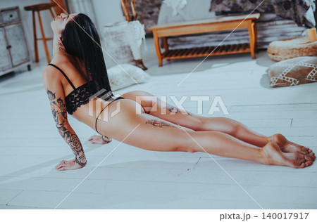 Young woman in lingerie with tattoos does yoga stretching Young woman in lingerie with tattoos does yoga stretching 140017917