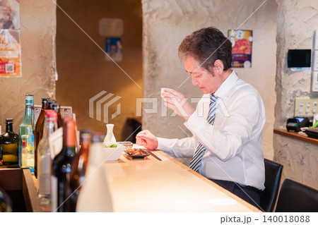 居酒屋で一人でカウンター席に座る高齢の男性 居酒屋で一人でカウンター席に座る高齢の男性 140018088