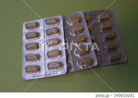 Blister Pack of Brown Pills on Green Background 140018281