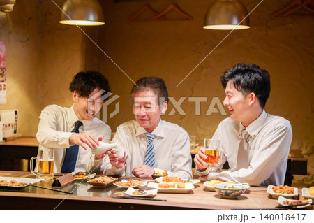 居酒屋で先輩にお酌をする若手社員 140018417