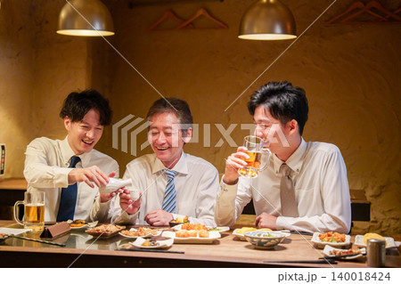 居酒屋で先輩にお酌をする若手社員 居酒屋で先輩にお酌をする若手社員 140018424
