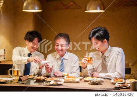居酒屋で先輩にお酌をする若手社員 居酒屋で先輩にお酌をする若手社員 140018426