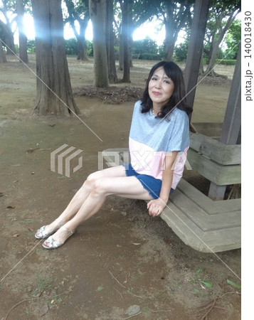 木陰で座る夏服の女性 140018430