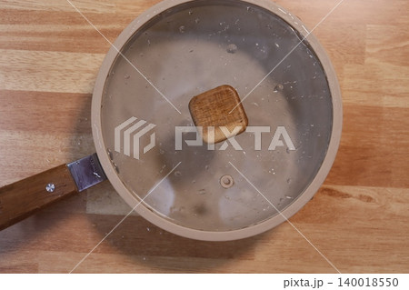 Pot with Glass Lid on Wooden Surface Pot with Glass Lid on Wooden Surface 140018550