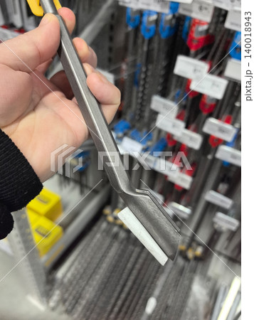 Unique metal tool held in hand surrounded by various hardware items Unique metal tool held in hand surrounded by various hardware items 140018943